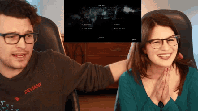 a man and a woman are laughing in front of a screen that says " the party "