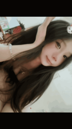 a woman with long hair is taking a selfie with a white flower on her head