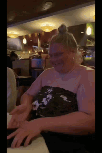 a woman is sitting at a table in a restaurant with her hands on the table