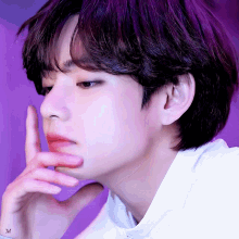 Taehyung rests his fingers near his lips in a purple-tinted thoughtful close-up.