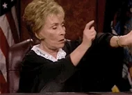 Judge Judy taps her watch impatiently while seated at the bench.