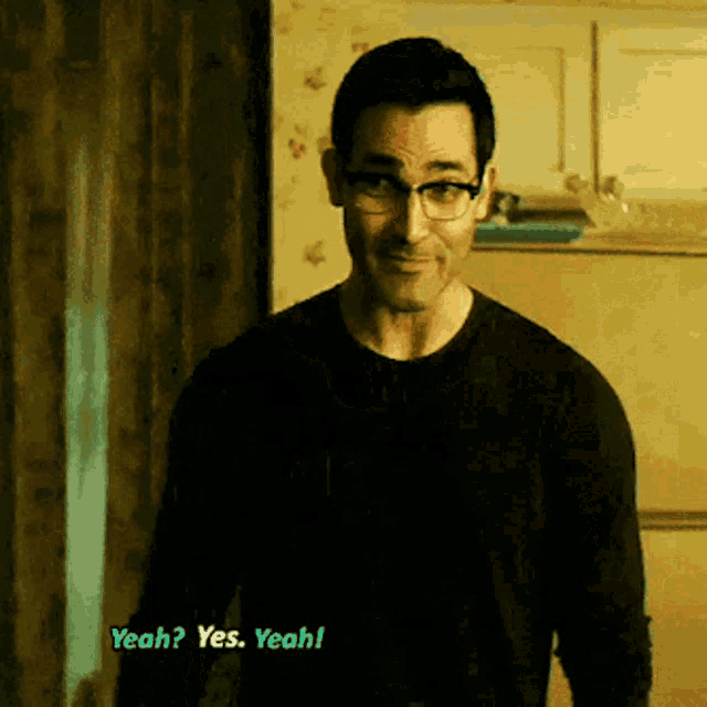 a man wearing glasses and a black shirt says yeah