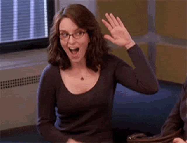 A woman laughs and gives herself a high five at a table.