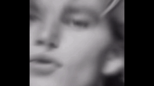 a black and white photo of a woman 's face with a blurry background .