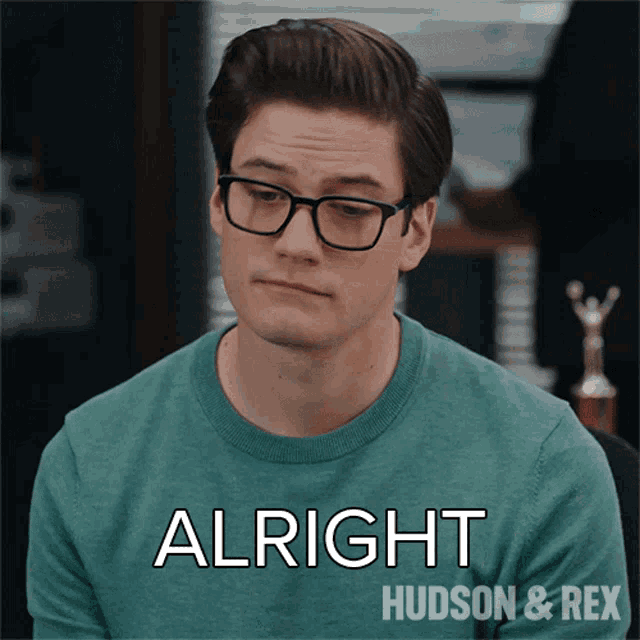 a man wearing glasses and a green sweater says alright