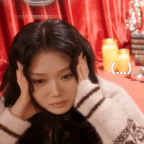 A woman at a brightly decorated table holds her head in stressed frustration.
