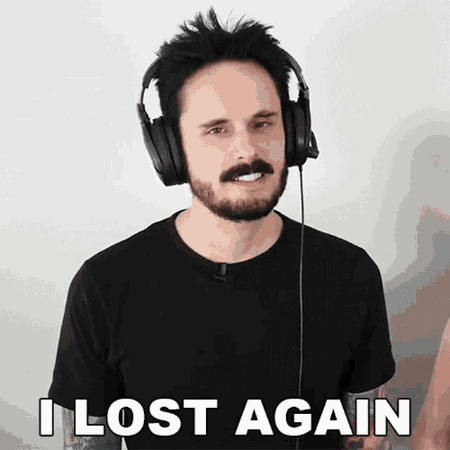 a man wearing headphones says " i lost again " in front of a white wall