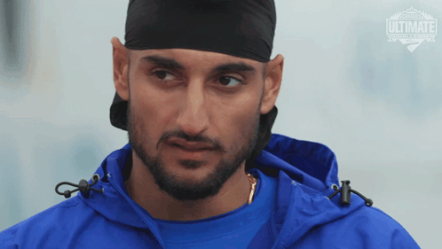 a man wearing a blue jacket and a black headband with ultimate written on the bottom