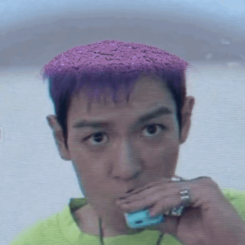 a man with purple hair is wearing a green shirt and a ring on his finger