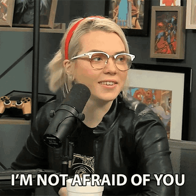 a woman talking into a microphone with the words " i 'm not afraid of you " next to her