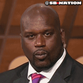 A bald man stares forward with a skeptical, pursed-lip expression.