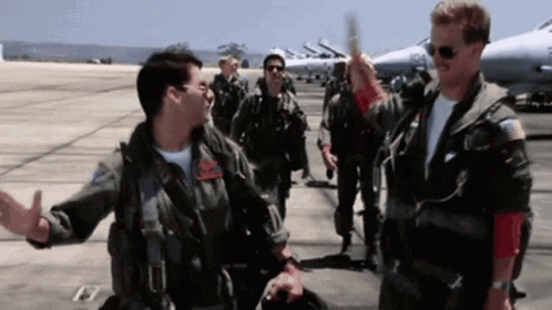 Two flight-suited pilots complete an outdoor high five.