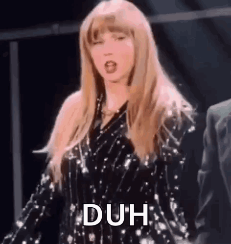 Taylor Swift flips her hair onstage with the caption “DUH”.