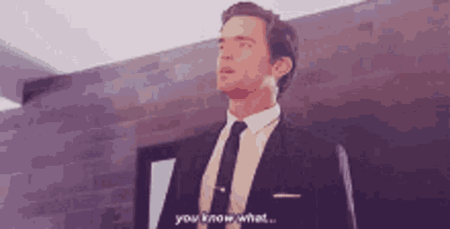 a man in a suit and tie is standing in a room and says " you know what "