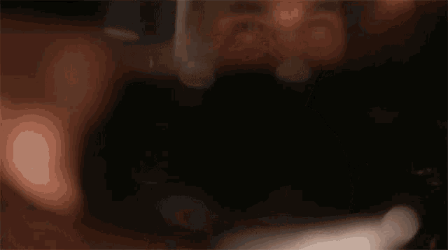 a man in a white shirt is holding a glass of wine in front of his face