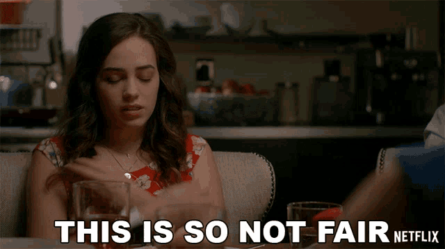 a woman sits at a table with a glass of water and says this is so not fair