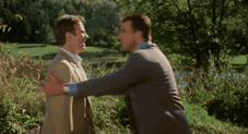 two men are hugging each other in a field