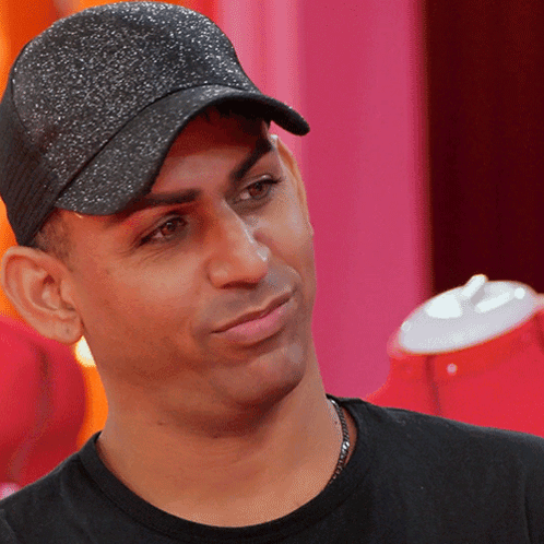 a man wearing a black hat and a black shirt looks at the camera