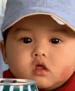 A baby in a cap looks forward with an astonished expression.
