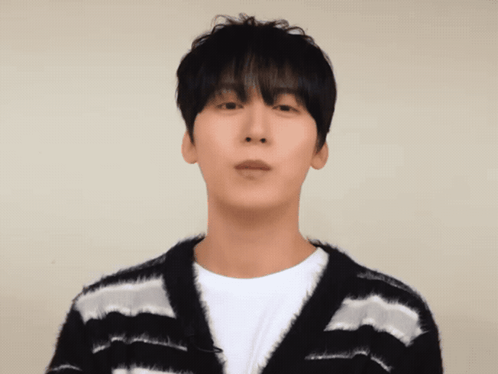 a man wearing a black and white striped sweater looks at the camera
