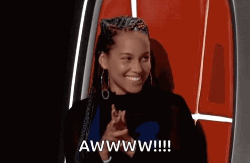 A woman applauds with a bashful smile under “AWWWW!!!!”