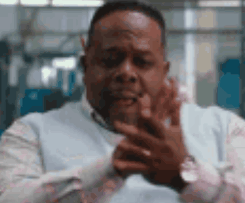 A man in a white shirt claps with a serious expression.