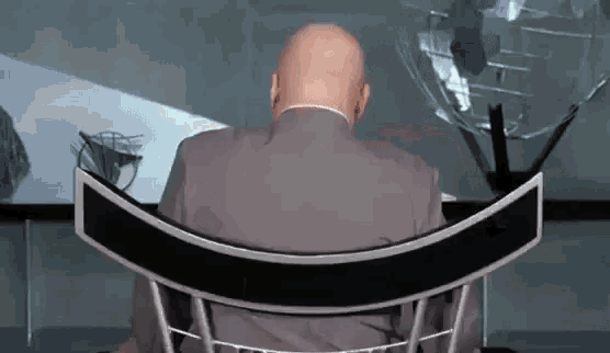 a man in a suit sits in a curved chair