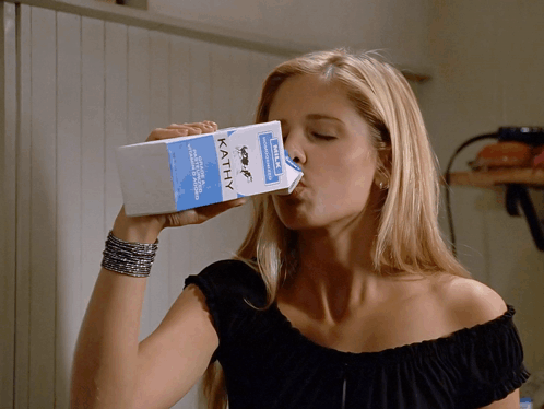 a woman is drinking from a carton of kathy milk