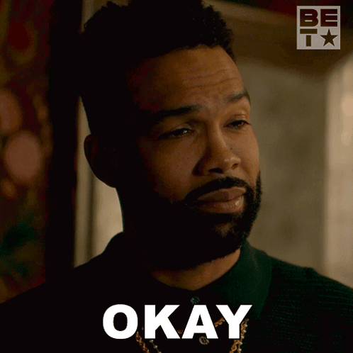 A man looks doubtful in a dim scene with “OKAY” text.