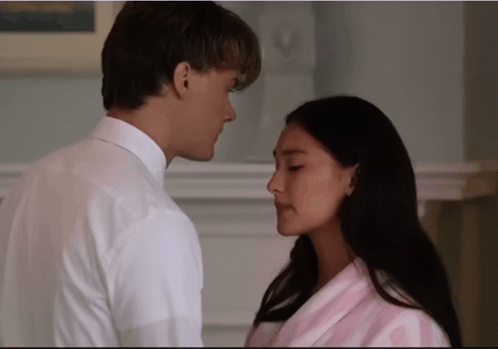 a man in a white shirt and a woman in a pink robe are looking at each other