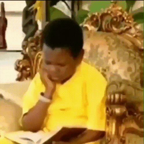 A child in a yellow shirt rests their chin on a hand, thinking.