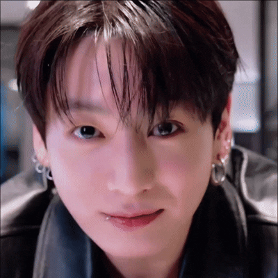A man leans close to the camera with a small warm smile.