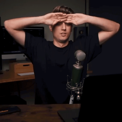a man standing in front of a microphone with his hands on his head