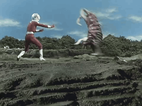 a man in a red superhero costume is fighting a monster in the dirt .