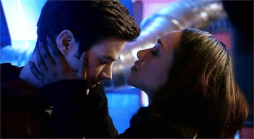 Barry and Iris kiss under blue party lights in The Flash.