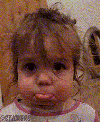 A little girl pouts with watery eyes and an exaggerated lower lip.