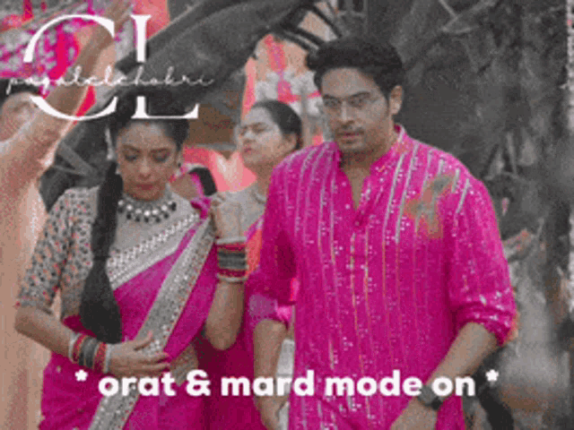 a man in a pink shirt stands next to a woman in a pink saree