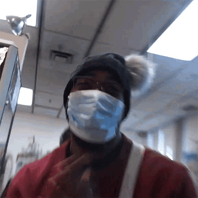 a man wearing a mask and a beanie looks at the camera