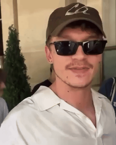 a man wearing sunglasses and a hat with the letter l on it