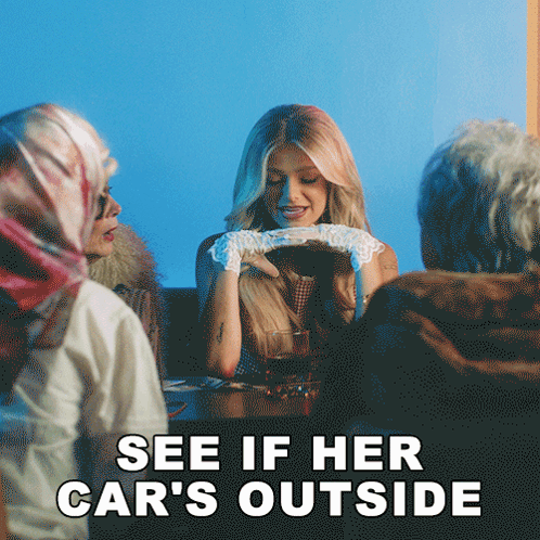 a woman is sitting at a table with a group of people and the caption says see if her car 's outside