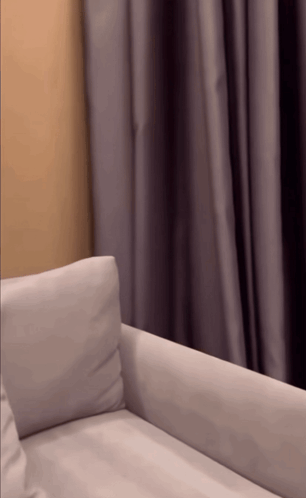 a white couch sits in front of a purple curtain
