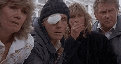 a group of people are looking at a man with a bandaged eye .