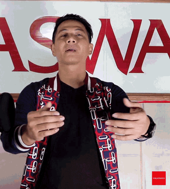 a man stands in front of a sign that says ' asna ' on it