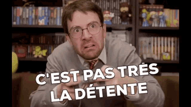 a man wearing glasses and a tie is playing a video game with the words " c'est pas tres la detente " above him