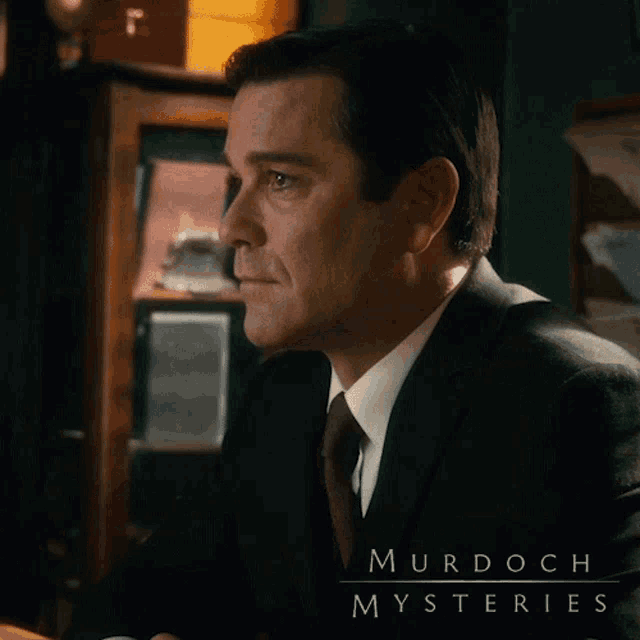 a man in a suit and tie with murdoch mysteries written above him