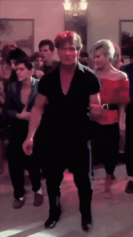 a man in a black shirt is dancing with a group of people
