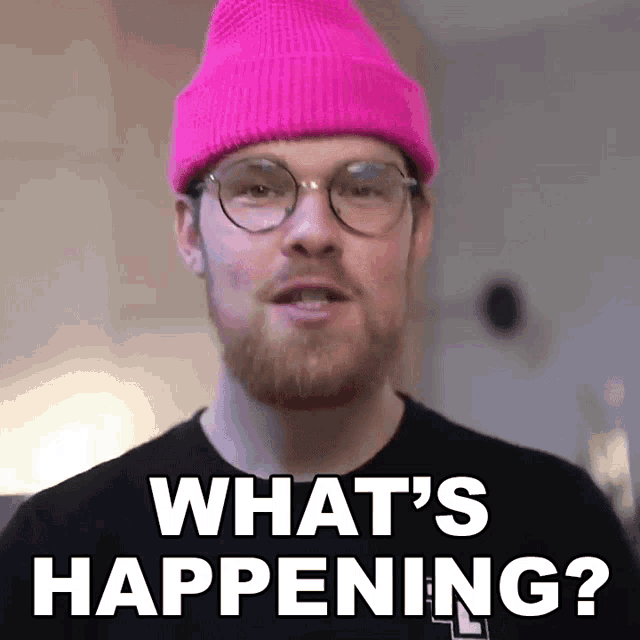 a man wearing glasses and a pink beanie is asking what 's happening