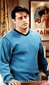 Joey Tribbiani from Friends stands with a hesitant expression.