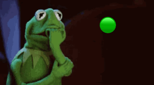 Kermit the Frog nervously watches a bright green ball in the dark.