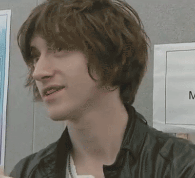 a close up of a young man 's face with a sign that says m in the background